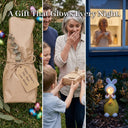 Three-panel gift scene showing OUTWAY Hoppi A004 solar rabbit wrapped in kraft paper with Happy Mothers Day Mum tag beside Easter eggs on the left a grandmother receiving the gift from grandchildren in the centre and the sitting rabbit glowing warm light in a garden at night on the right with text overlay A Gift That Glows Every Night