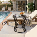 Outdoor patio scene with lounge chairs, a table, and pool in the background