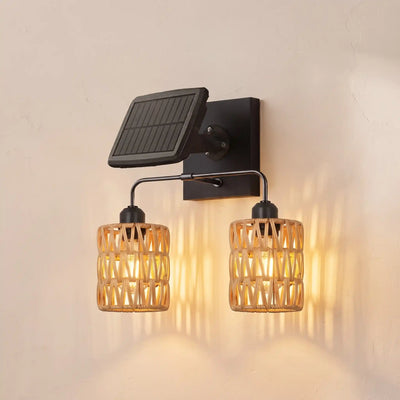 A wall-mounted solar-powered double light fixture with a black metal bracket and solar panel, featuring two woven bamboo shades that glow with warm light against a beige wall.