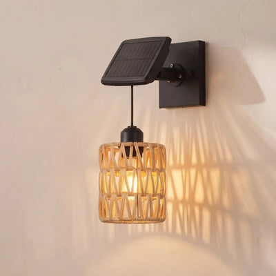 Solar wall sconce with a black wall mount and solar panel, featuring a warm glowing woven rattan shade, mounted on a textured beige wall.