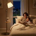 FL068 antique brass arc floor lamp with wood tray beside a bed, warm 3000K glow, mother and young child reading a bedtime storybook together in a softly lit bedroom