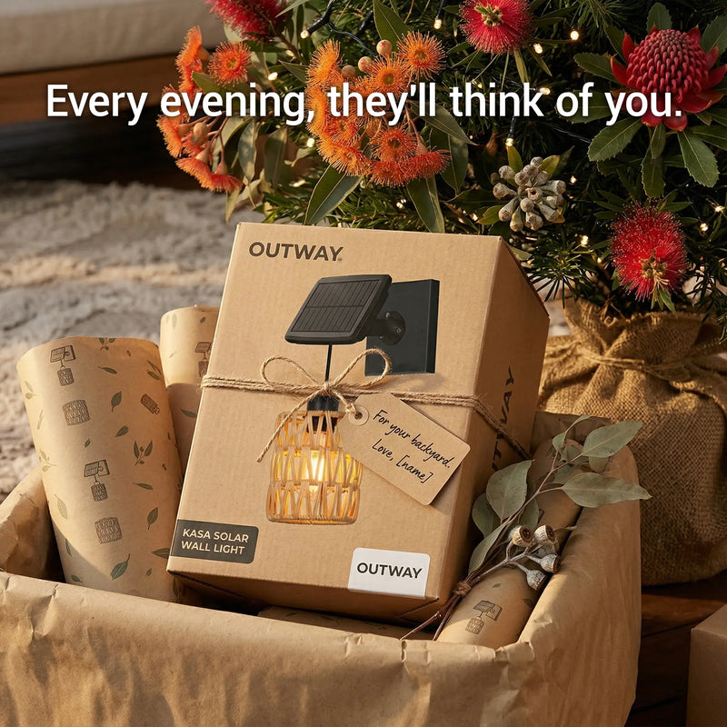 Gift-wrapped PT0909 Kasa Solar Wall Light box from OUTWAY, nestled among native flowers and twine — “Every evening, they’ll think of you” tagline emphasizes emotional value as housewarming or Mother’s Day gift.