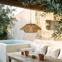 HAIKU solar bamboo pendant light hanging above outdoor dining table under pergola at dusk — warm golden glow