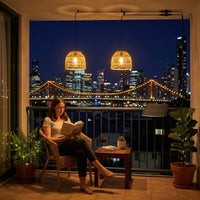 Woman reading on balcony at night with city bridge lights in background, illuminated by PT0914 pendants — perfect blend of urban view and cozy, solar-powered ambiance.
