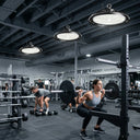 Three Outway high bay LED lights illuminating a busy commercial gym.