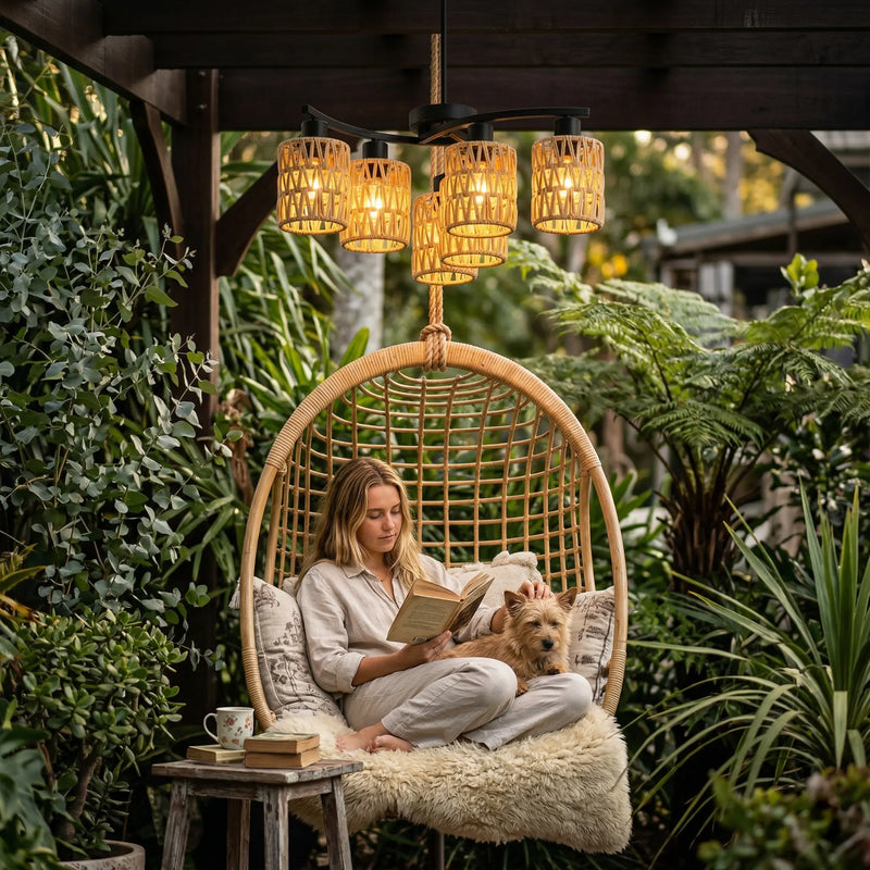 Woman reading a book with a dog on her lap in a hanging chair surrounded by plants.