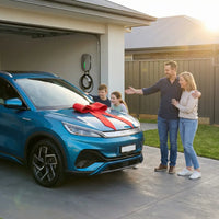 Family with a blue BYD electric car featuring a red bow, with an Outway EV05 wall-mounted charger installed in the garage background, showcasing home EV charging solution.