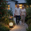 Man and woman walking together in a garden with a decorative lantern and flowers.