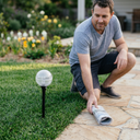 Man kneeling on grass next to a solar lamp in a garden