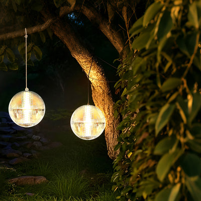 outdoor solar ball lights hanging from a tree branch at night.