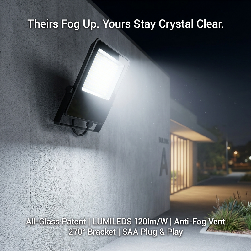 A night shot of the E017EI Fano LED Floodlight mounted on a concrete wall, emphasizing the "Crystal Clear" glass lens that stays fog-free, contrasting with competitors' lights that fog up over time.