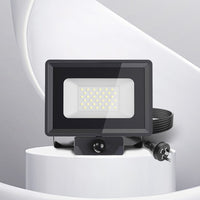 Black LED sensor floodlight on a white pedestal with a gray background