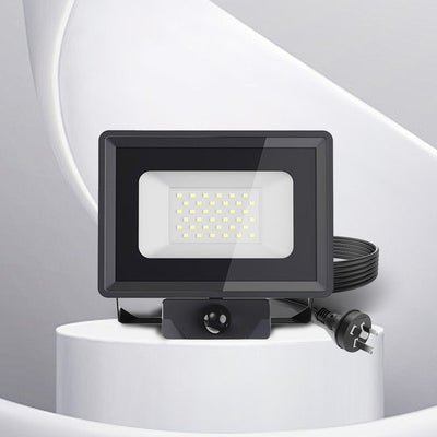 Black LED sensor floodlight on a white pedestal with a gray background