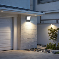 LED floodlight mounted on a wall, illuminating the area with white light, is placed above a garage entrance.