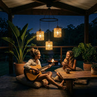 Two women on a wooden deck at night, one playing guitar and the other holding a drink.