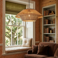 A large woven natural-fiber pendant light hangs over a cozy window seat in a warm, rustic room with wood paneling, a bookshelf, and a brown sofa.