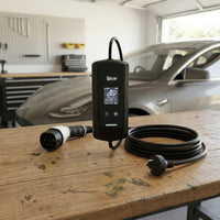 Car charging cable and adapter on a wooden table with a car in the background