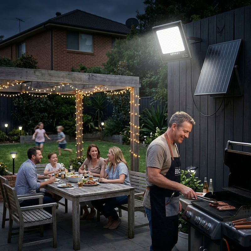 Family gathered around a table in a backyard with a solar light fixture and grill.