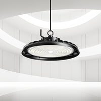 Black LED light high bay fixture hanging in a modern interior setting with white walls.
