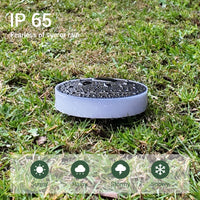 Round solar light resting on green grass, designed to be waterproof for outdoor use.