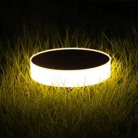Round solar light glowing on grass at night