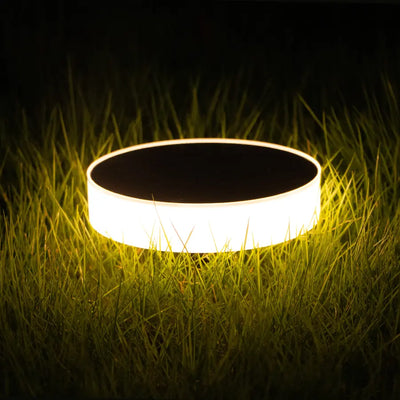 Round solar light glowing on grass at night