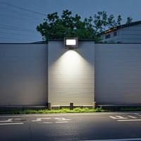 A lit LED sensor floodlight shines brightly on a wall, enhancing visibility in the surrounding area