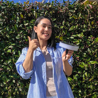 Woman holding a Round solar garden light with greenery in the background