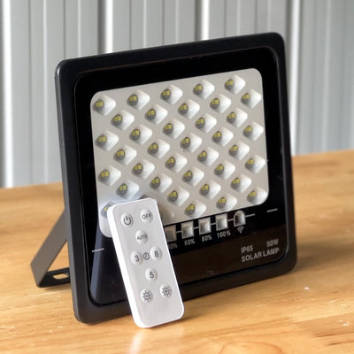 Solar flood light with remote control on a wooden surface