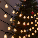 A decorative string of yellow LED solar fairy lights with a blurred Christmas tree in the background