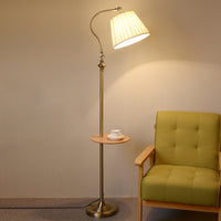 Gold floor lamp with tray for books or decor.