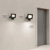 Two black wall-mounted floodlights shown on a light gray wall with overlaid height measurements (147mm, 171mm, and 2000mm) relative to a gray door.