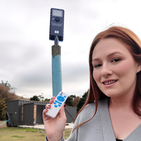 Woman holding a remote control with a solar sensor floodlight in the background