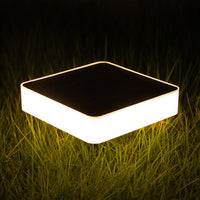 Square outdoor solar ground lights on grass at night