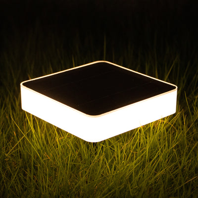 Square outdoor solar ground lights on grass at night