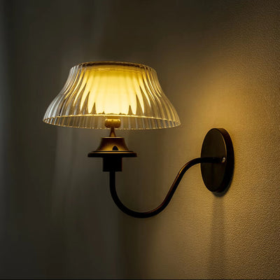 Wall-mounted solar wall light with pleated glass shade on a dark wall